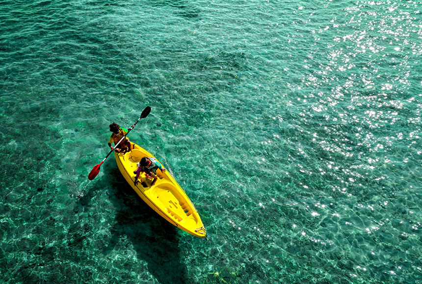 Two people on a yellow canoe in a glistening sea
